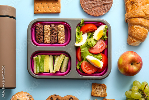 Lunchbox with delicious food and thermos on blue background