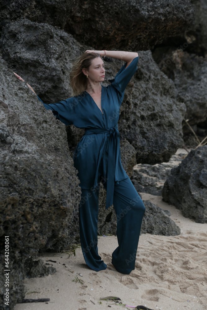 Portrait of beautiful young woman in fashionable green silk outfit on empty wild beach, idylic summer vacation far away from city. Elegant and stylish summertime clothes, spring-summer fashion trend. Portrait of beautiful young woman in fashionable green silk outfit on empty wild beach, idylic summer vacation far away from city. Elegant and stylish summertime clothes, spring-summer fashion trend.