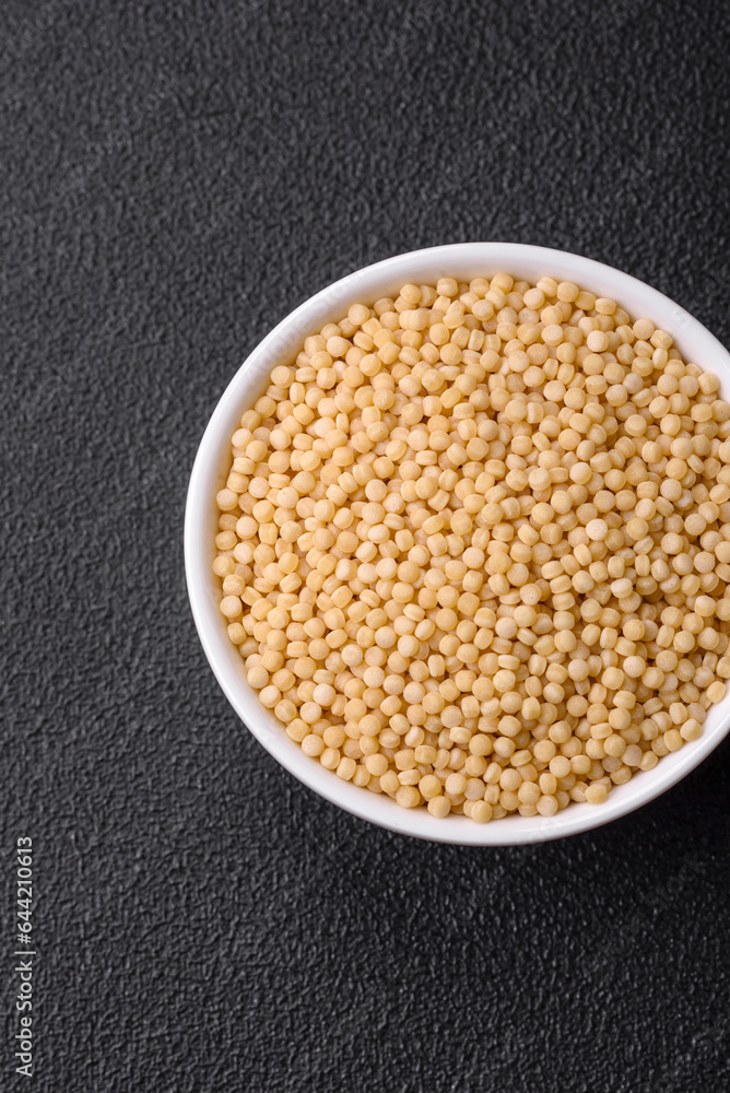 Raw ptitim pasta in a ceramic bowl on a dark concrete background Raw ptitim pasta in a ceramic bowl on a dark concrete background