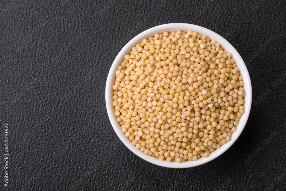 Raw ptitim pasta in a ceramic bowl on a dark concrete background Raw ptitim pasta in a ceramic bowl on a dark concrete background
