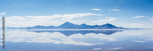 Midday over a salt lake, glass - like water reflecting the blue sky, distant mountains on the horizon, minimalistic composition