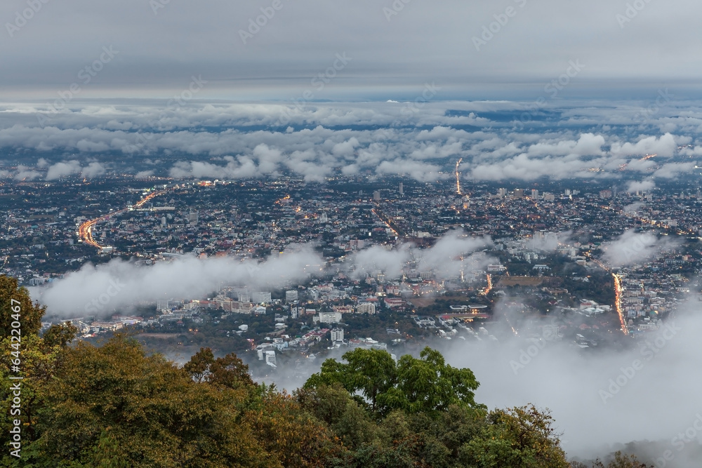 Beatiful Chiang Mai town view from the mountain. City under clouds at sunset on rainy day.