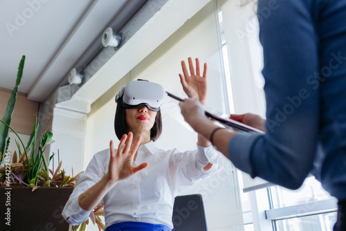 Foto sitting asian woman wearing viewer exploring virtual reality with her colleague