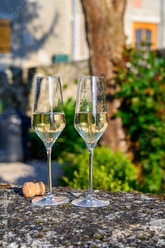 Tasting of premier cru sparkling white wine with bubbles champagne with view on old houses of Hautvillers, where lived Benedictine monk how developed champagne wine, France.