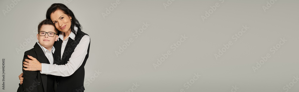 businesswoman hugging son with down syndrome in school uniform on grey, supportive parent, banner businesswoman hugging son with down syndrome in school uniform on grey, supportive parent, banner