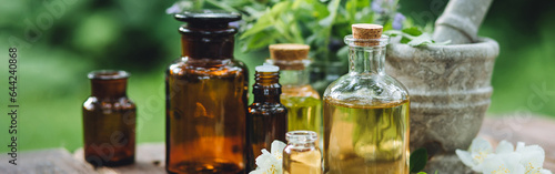 Herbal pure natural cosmetic ingredients on wooden background. Mix of holistic flowers and herbs, salt, massage herb-infused essential oil in glass bottles. Aromatherapy, fragrance production. Banner