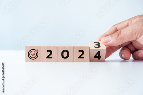 2024 Happy New Year's Eve wooden blocks flip change hand white background. Countdown starting ending 2023 action schedule calendar strategy future vision. Business startup plan resolution celebration.