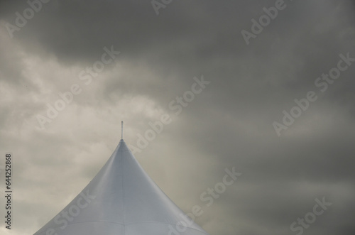 Top half of carnival big top tent with dark grey skies and cloud background 