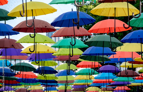 many colorful umbrellas fly and hover on the city street