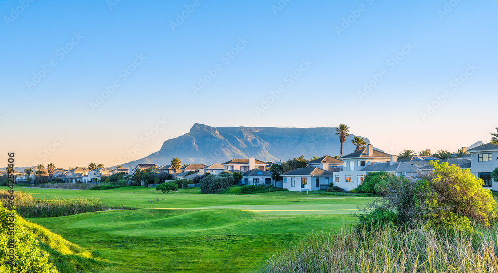 Fototapeta premium Panorama shot golf course and the table muntain in the background during sunset, Cape Town, South Africa