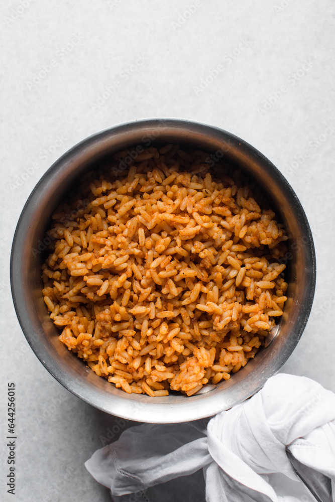Jollof rice and fried chicken in a silver saucepan, homemade nigerian jollof rice in a pot, overhead view of authentic homemade west african jollof rice Jollof rice and fried chicken in a silver saucepan, homemade nigerian jollof rice in a pot, overhead view of authentic homemade west african jollof rice