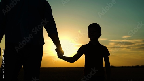 Little son, dad hold hands close up in nature in sun. Child father walk in park at sunset, family trust concept. Parent, kid boy outing together. Adoption of child. Happy family, teamwork. Silhouette