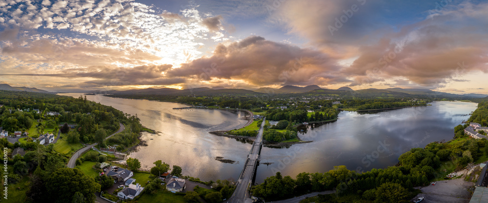 Aerial panorama view of Kenmare Bay at the entrance of the Ring of Kerry in Ireland, Our Lady's Bridge crossing the water, stunning colorful sunset reflecting off the water