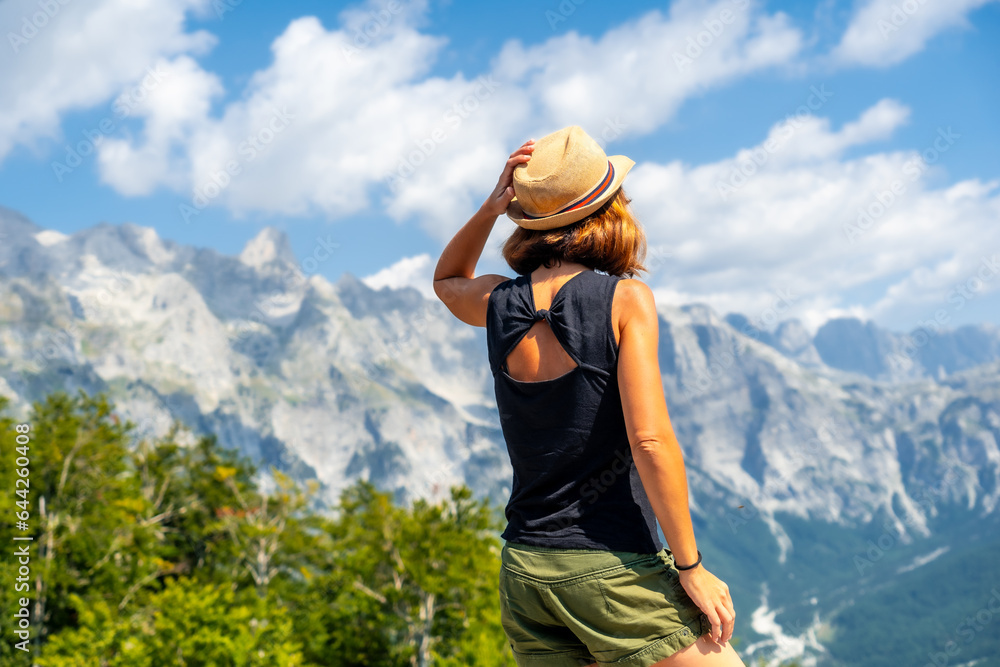 A tourist woman with hat on the mountain peaks of Theth national park valley, Albania. Albanian Alps