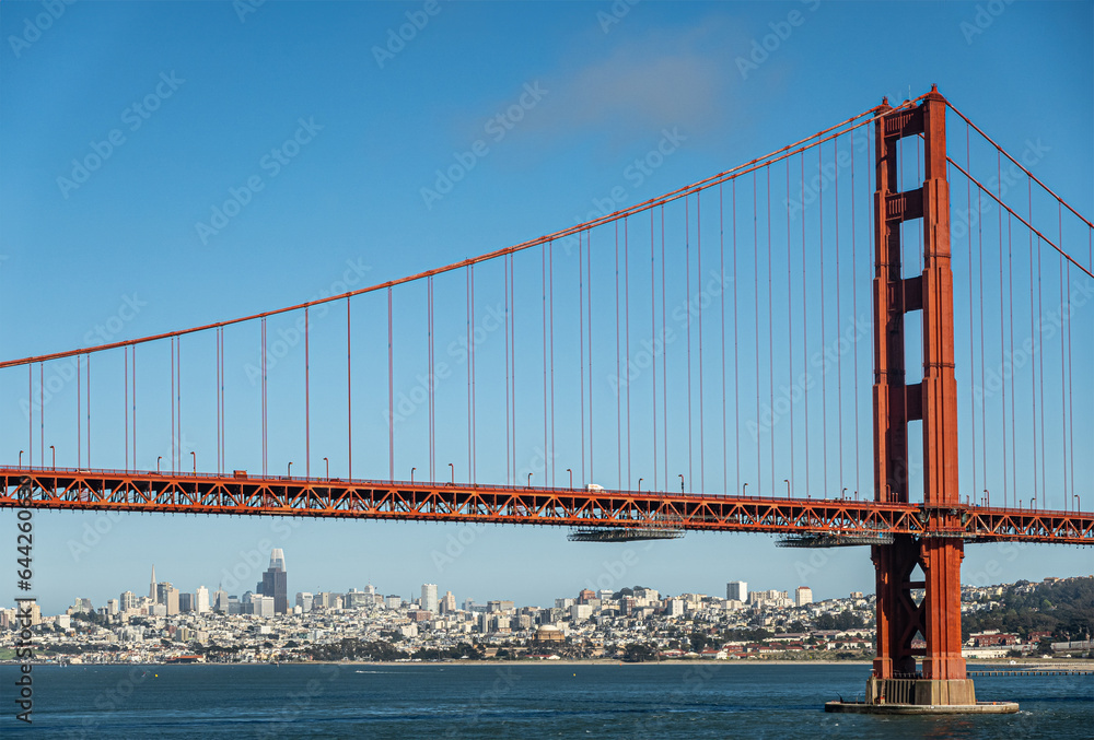San Francisco, CA, USA - July 13, 2023: Downtown urban jungle seen from under Golden Gate bridge, with 1 tower, on ocean side under blue sky, behind blue bay water