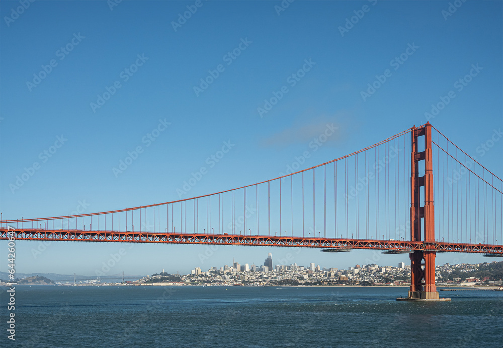 San Francisco, CA, USA - July 13, 2023: Approaching downtown urban jungle, seen from ocean side Golden Gate bridge, with 1 tower, under blue sky, behind blue bay water