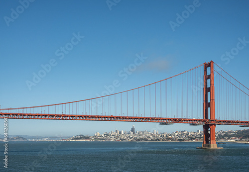 San Francisco, CA, USA - July 13, 2023: Approaching downtown urban jungle, seen from ocean side Golden Gate bridge, with 1 tower, under blue sky, behind blue bay water