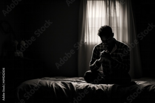 Intimate portrayal of a kneeling male aged 20 praying in his bed
