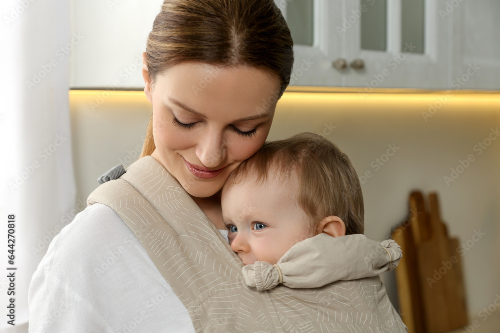 Mother holding her child in sling (baby carrier) at home Mother holding her child in sling (baby carrier) at home