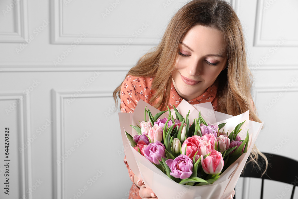 Young woman with bouquet of beautiful tulips indoors. Space for text Young woman with bouquet of beautiful tulips indoors. Space for text