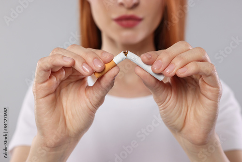 Stop smoking concept. Woman breaking cigarette on light gray background, closeup