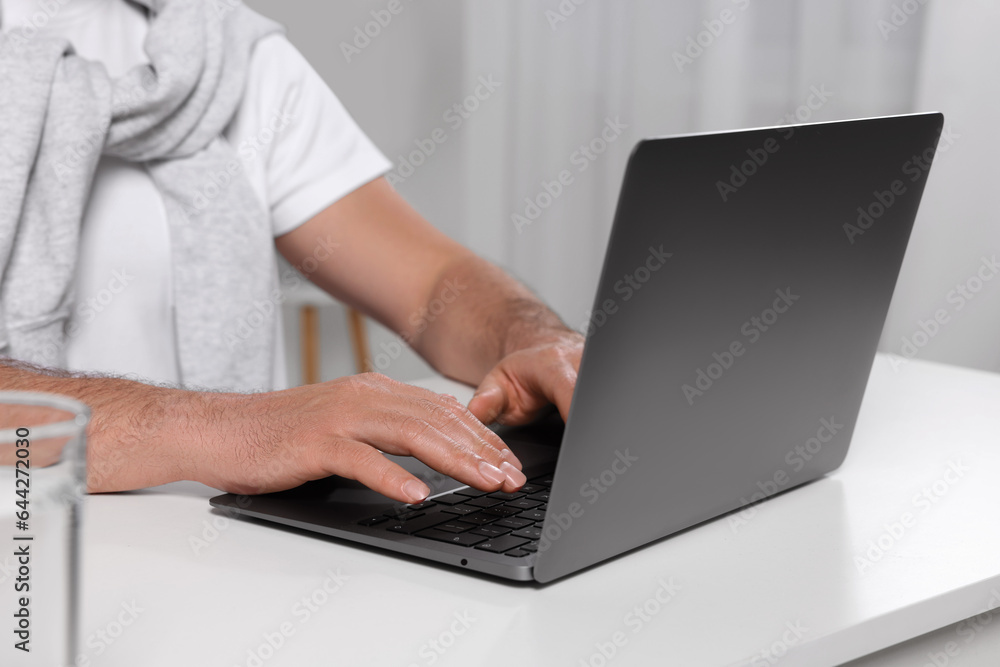 Fototapeta premium Man using laptop at white table indoors, closeup
