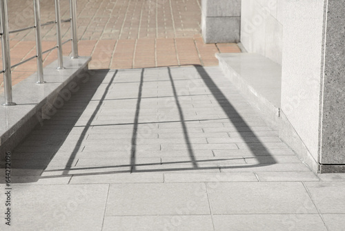 Tiled ramp with metal handrail near building outdoors