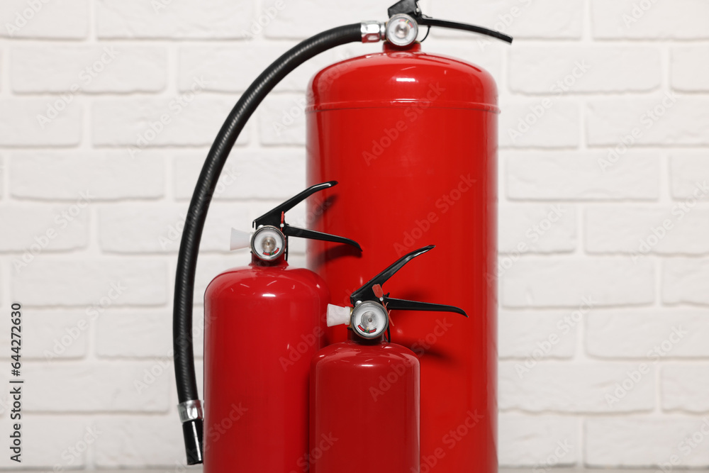 Obraz premium Red fire extinguishers near white brick wall