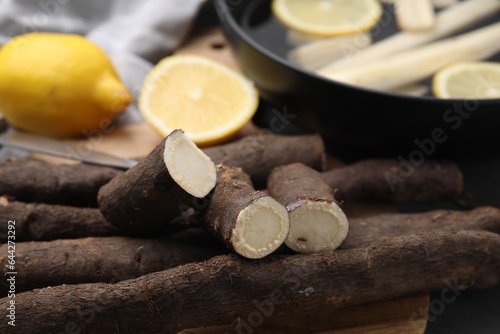 Raw salsify roots with lemon on table, closeup photo