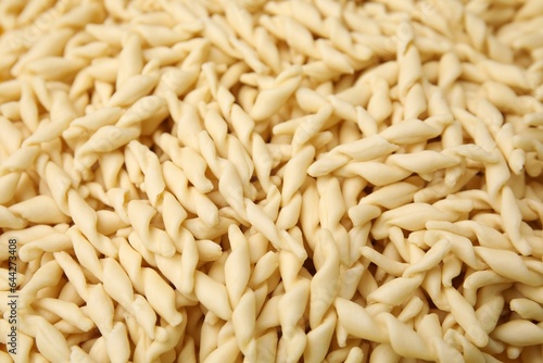 Uncooked trofie pasta as background, closeup view
