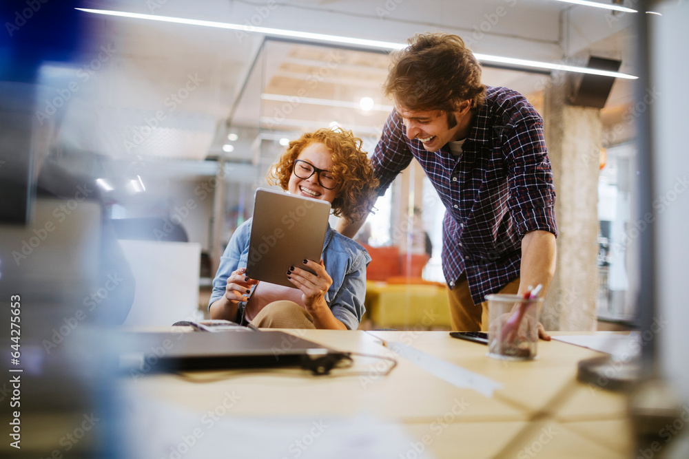 Young Caucasian woman and man using the tablet in the office of a startup company Young Caucasian woman and man using the tablet in the office of a startup company