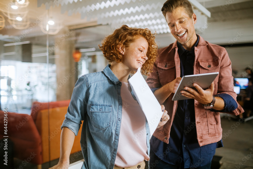 Young Caucasian woman and man using the tablet in the office of a startup company Young Caucasian woman and man using the tablet in the office of a startup company