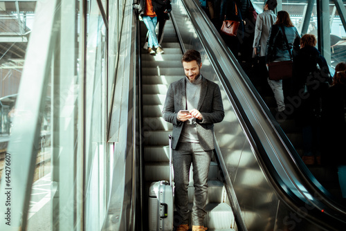 Young man using a smartphone on an escalator in a train station