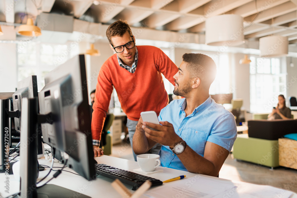Young diverse coworkers using a smartphone in a startup company office Young diverse coworkers using a smartphone in a startup company office