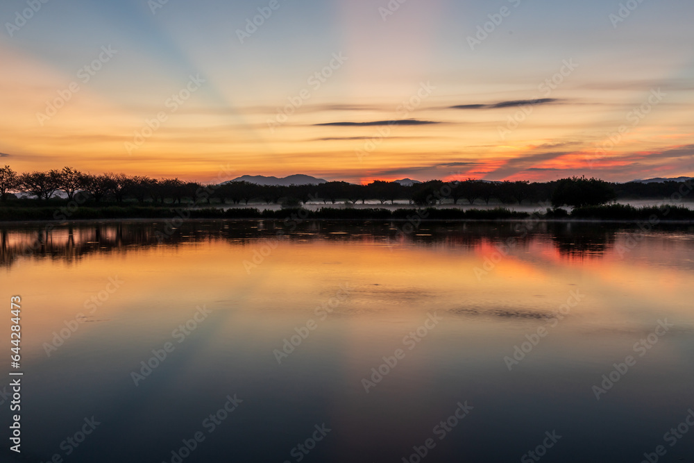 茨城県母子島遊水池の水面に映る朝焼けの筑波山と日の出の光芒