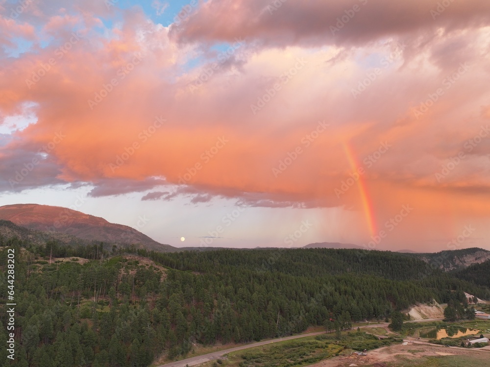 Moonrise along with sunset and rainbow over the mountains