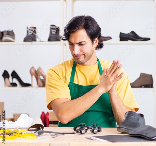 Young man repairing shoes in workshop