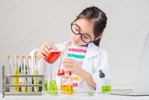 Asian little girl working with test tube science experiment in white classroom