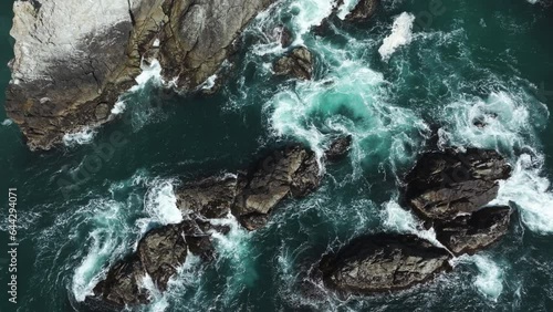 Aerial view rotating above rocks in waves in sunny Big Sur, California, USA