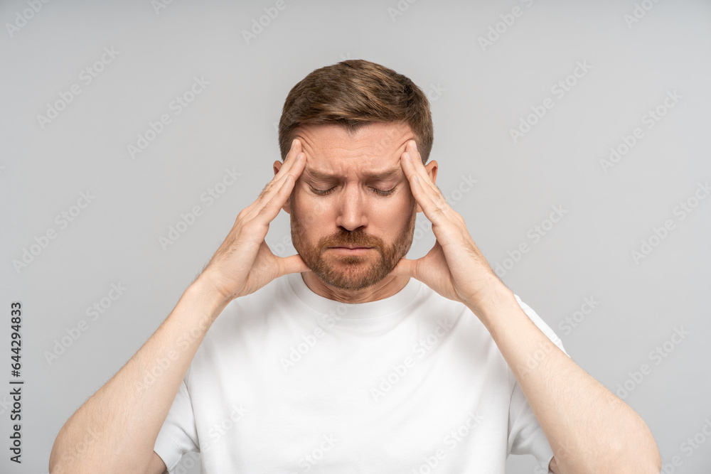 Irritated exhausted man with eyes closed presses fingers to temples from headache, failure, fatigue, difficult choose, isolated background. Overwhelmed male with professional burnout tries concentrate Irritated exhausted man with eyes closed presses fingers to temples from headache, failure, fatigue, difficult choose, isolated background. Overwhelmed male with professional burnout tries concentrate