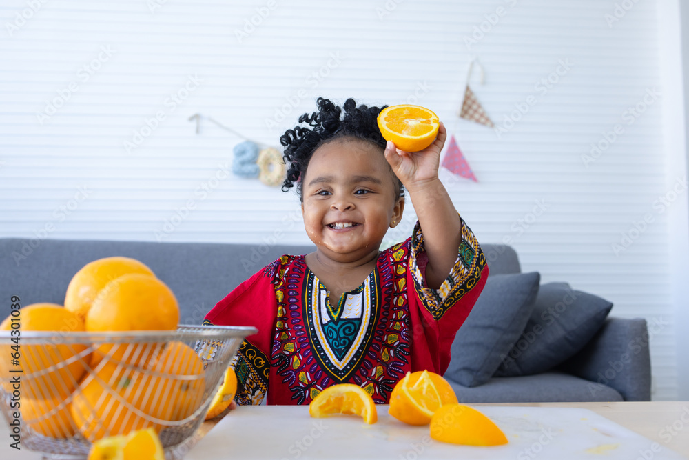 Cute African baby girl showing the halved orange fruit in hand. Cute African baby girl showing the halved orange fruit in hand.