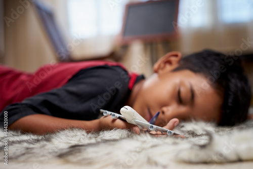 Young boy fall asleep holding airplane toy at home