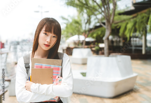 Portrait of standing asian woman university student wear backpack with stationery