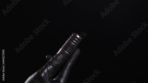 Girl in black latex gloves inserts a cartridge into a permanent makeup and tattoo machine.  The concept of cosmetology procedures