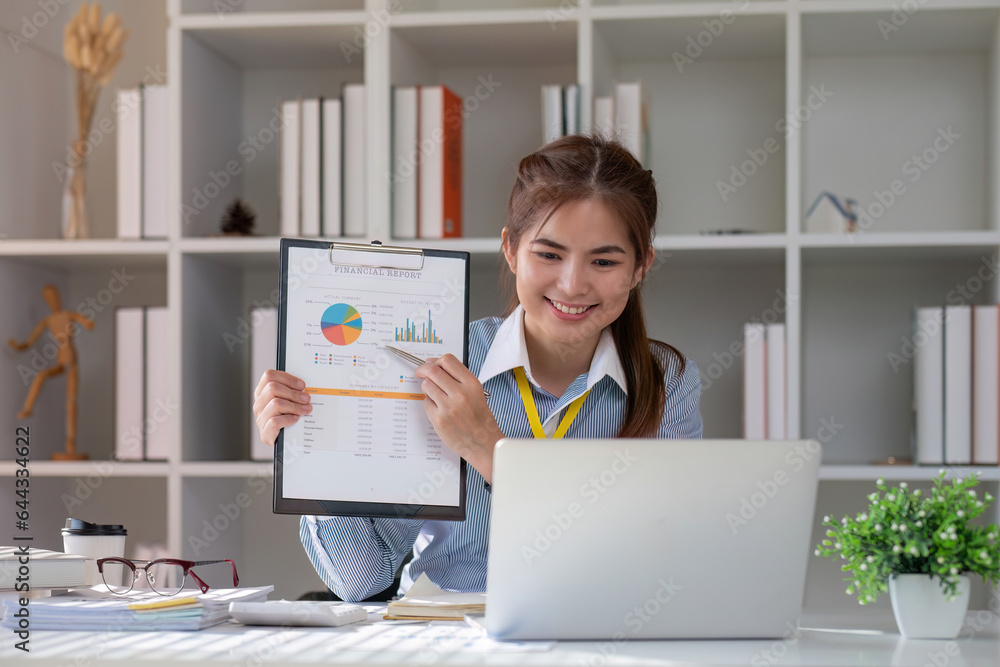 Paperwork. Happy smiling asian business woman in formal wear sitting at wooden desk in modern office and reading report document.