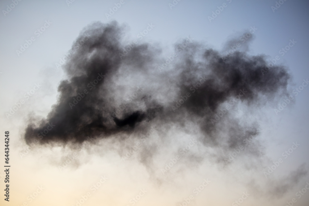Fototapeta premium Black smoke against a blue sky