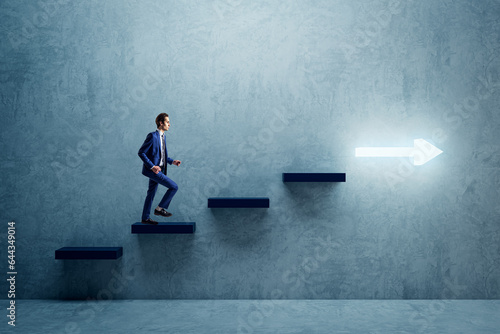 фотографія Side view of young businessman climbing illuminated arrow stairs to success on concrete wall background in interior