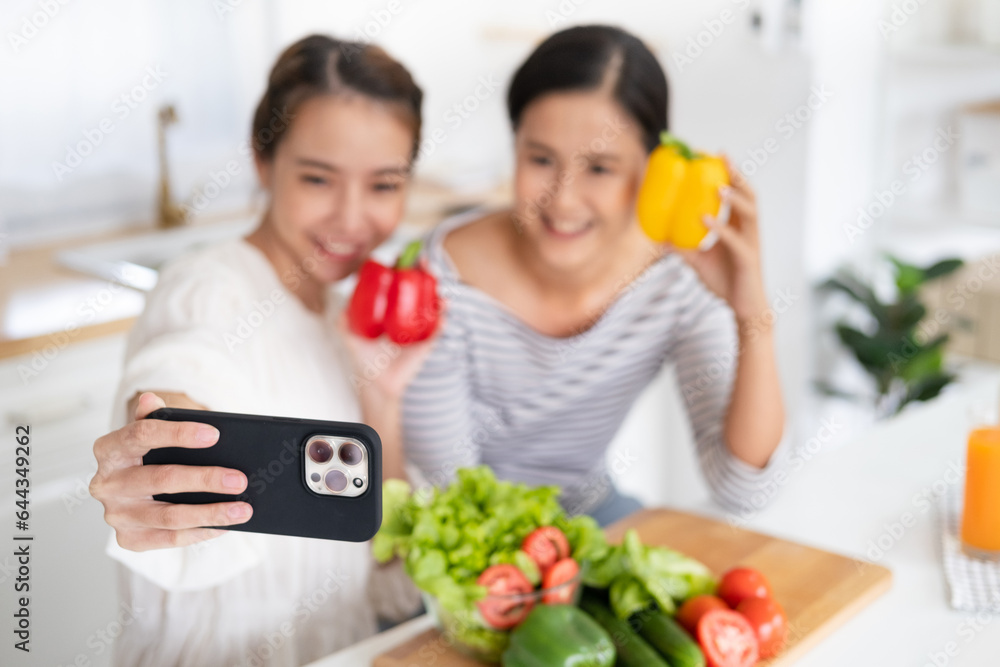 Asian woman girlfriends smiles, holds bell pepper and takes selfies in kitchen