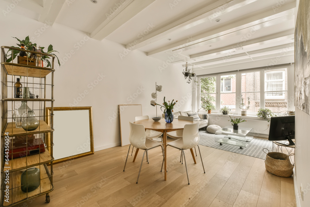 a living room with white walls and wood flooring the room is decorated with plants, furniture and an open window