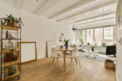 a living room with white walls and wood flooring the room is decorated with plants  furniture and an open window